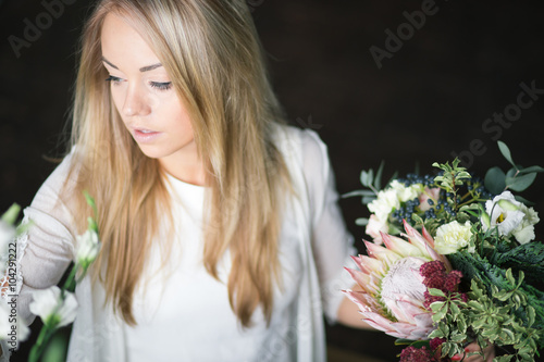 Florist at work: pretty young blond woman making fashion modern bouquet of different flowers © cherry_d