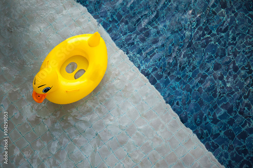Top view of pool with yellow duck toy floating - relaxation concept