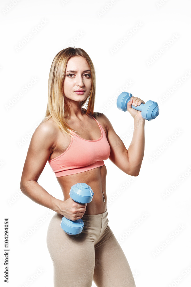 Beautiful young girl with a sports body with dumbbells on a white studio background Beautiful young girl with a sports body with dumbbells on a white studio background