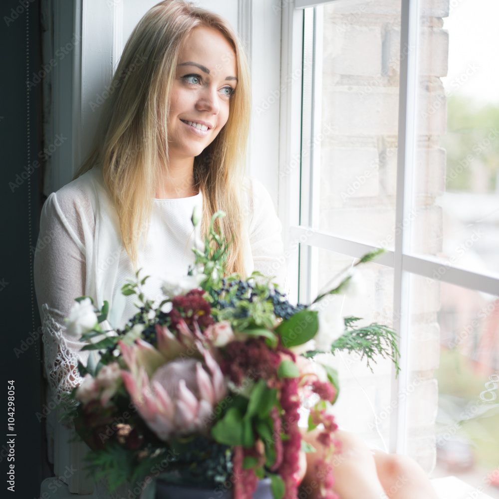 Florist at work: pretty young blond woman holds fashion modern bouquet of different flowers Florist at work: pretty young blond woman holds fashion modern bouquet of different flowers