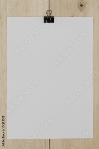 white paper with paperclip on wooden background.