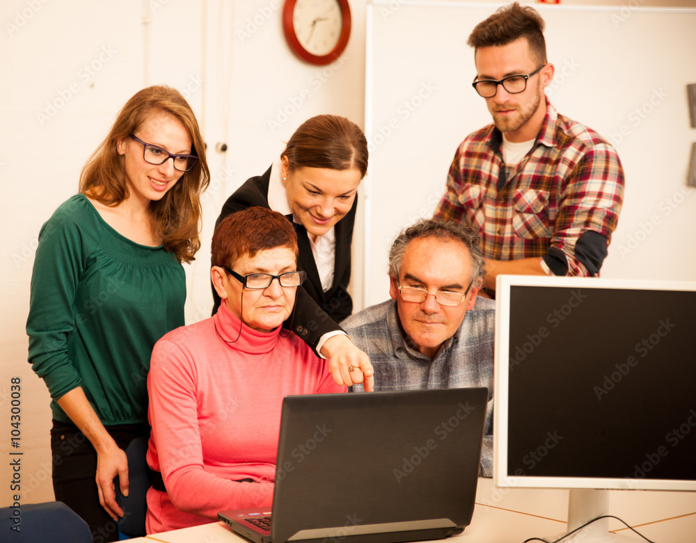 Group of adults learning computer skills. Intergenerational tran Group of adults learning computer skills. Intergenerational tran