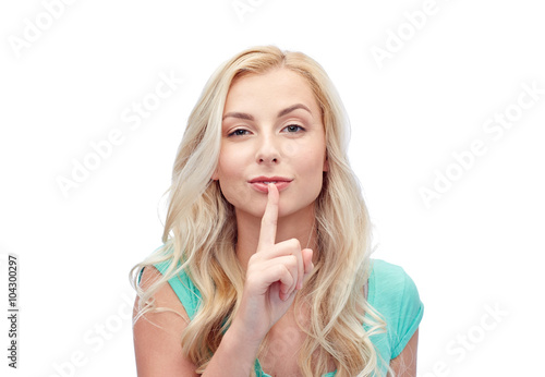 beautiful young woman holding finger at her lips