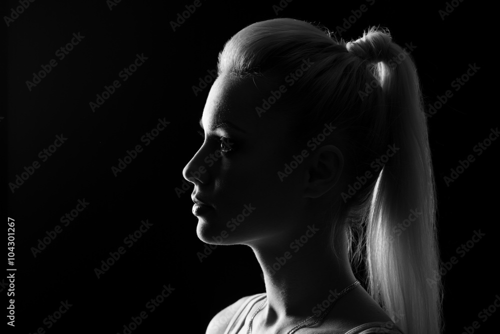 Woman portrait silhuette in darkness with soft light on face.