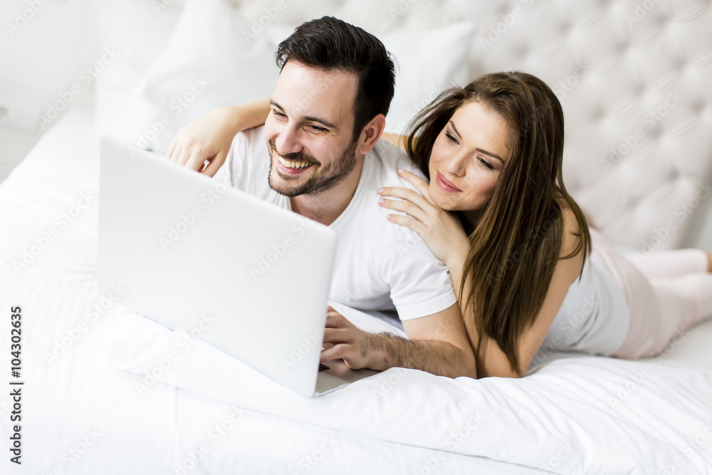 Young couple with laptop in the bed Young couple with laptop in the bed