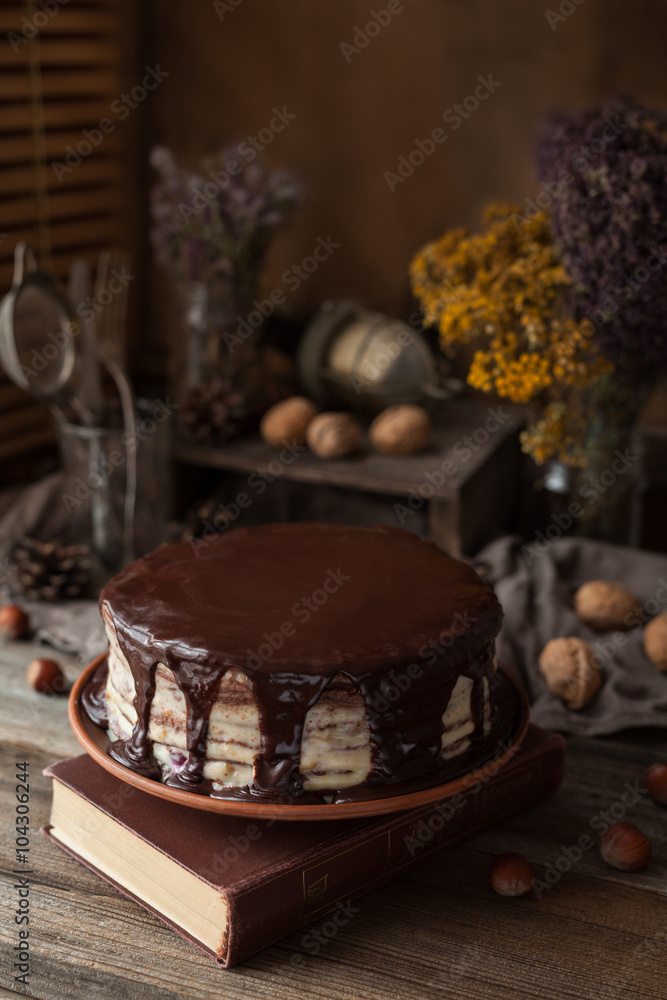 Chocolate cake composition with book, herbs and walnuts. Rustic style on vintage wooden table background.