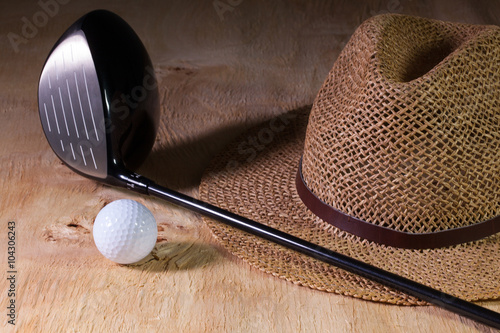 Siesta - straw hat and golf driver on a wooden desk photo