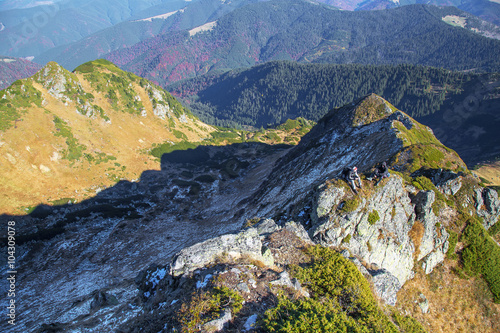 two hikers sitting on high mounain peak, aerial view