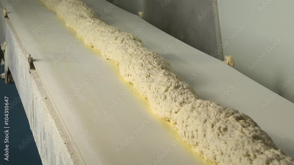 In bread bakery, food factory. Dough moves on a conveyor belt In bread bakery, food factory. Dough moves on a conveyor belt