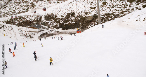 View from a ski lift of skiers below on a run at the ski resort and the mountain valleys stretching away into the distance below