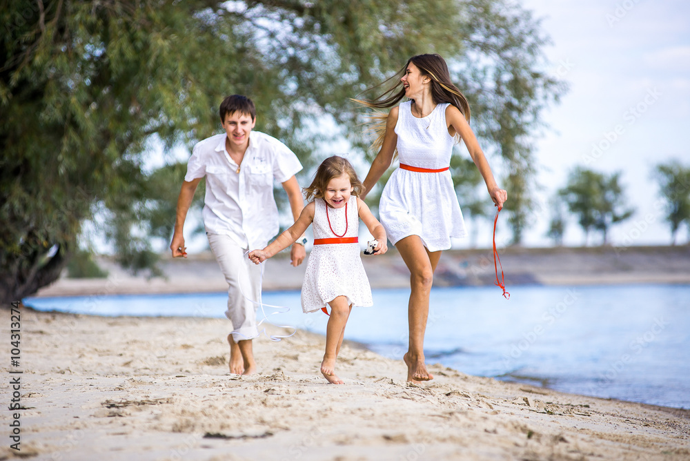 Mom, dad and daughter walking on the beach