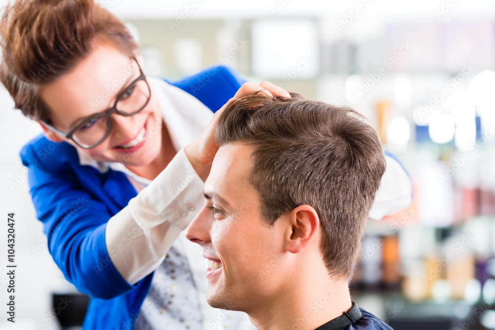 Fototapeta premium Friseurin schneidet Mann die Haare im Friseursalon 