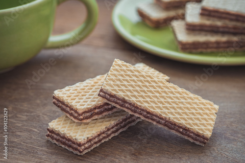 Wafers with chocolate on wooden table and coffee cup