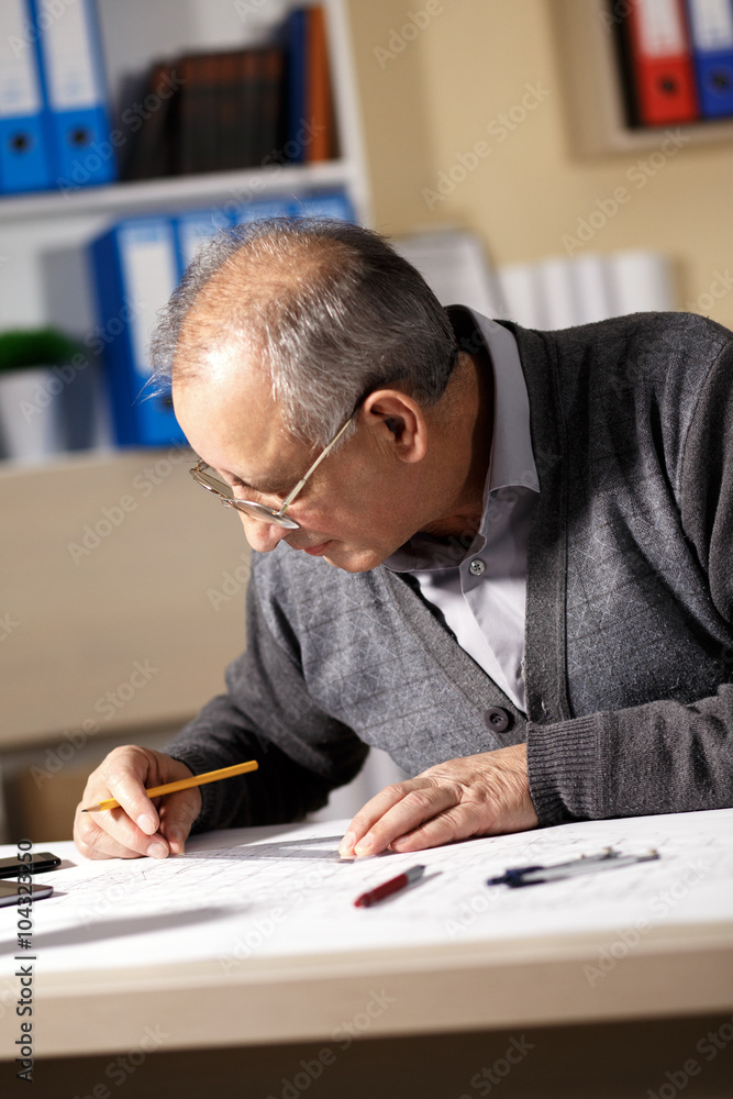 Senior architect working on construction blueprint in office, he draws with a pencil and ruler. Senior architect working on construction blueprint in office, he draws with a pencil and ruler.