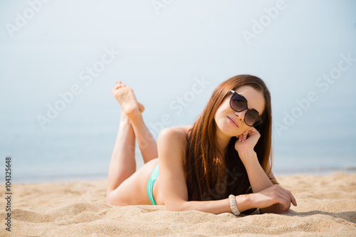 Beautiful sexy brunette lying on a sandy beach