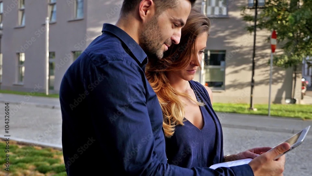 Businessman and businesswoman analyzing documents and charts on tablet pc. Outdoor photo. Businessman and businesswoman analyzing documents and charts on tablet pc. Outdoor photo.