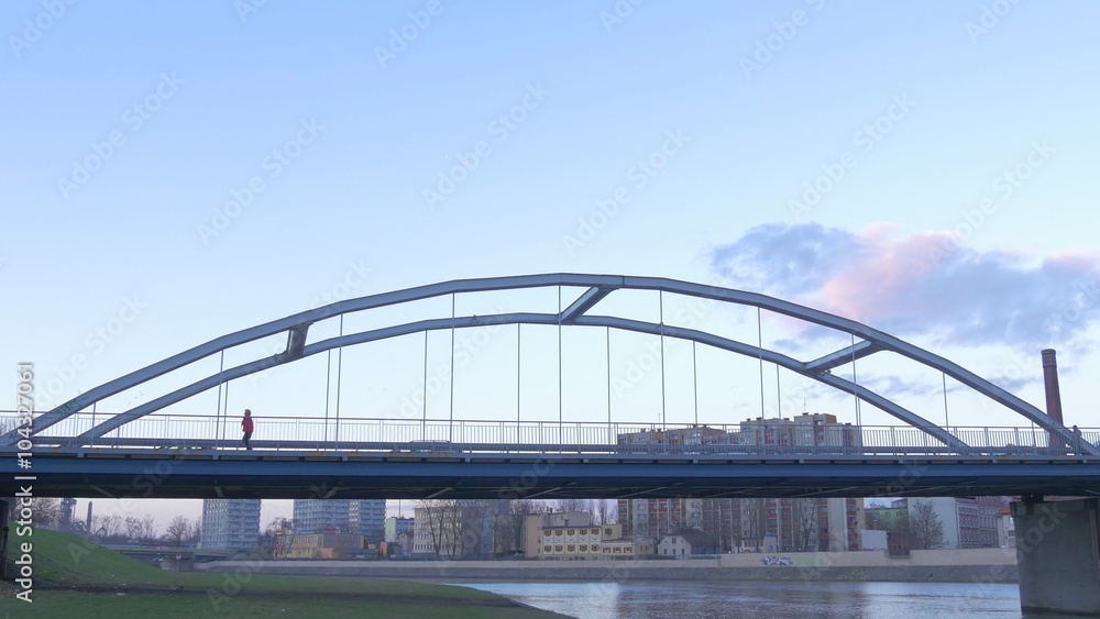 People Silhouettes Are Walking by Arch Bridge Cars Minibuses Are Driven by a Bridge Upon a River People on a Bridge Multi-Storeyed Houses Cityscape People Silhouettes Are Walking by Arch Bridge Cars Minibuses Are Driven by a Bridge Upon a River People on a Bridge Multi-Storeyed Houses Cityscape