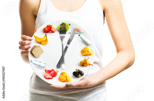 Canvastavla Beautiful young woman holding a plate with food, diet and time concept close up