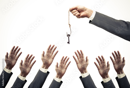 hand of a businessman holding a fish hook with a key over many hands of businessmen - opportunist concept photo
