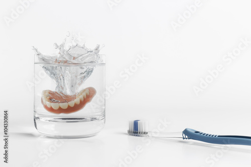 Dentures splashing in water with toothbrush