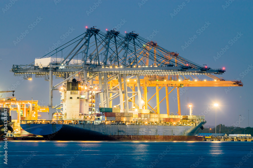 Fototapeta premium Container Cargo freight ship with working crane bridge in shipyard at dusk for Logistic Import Export