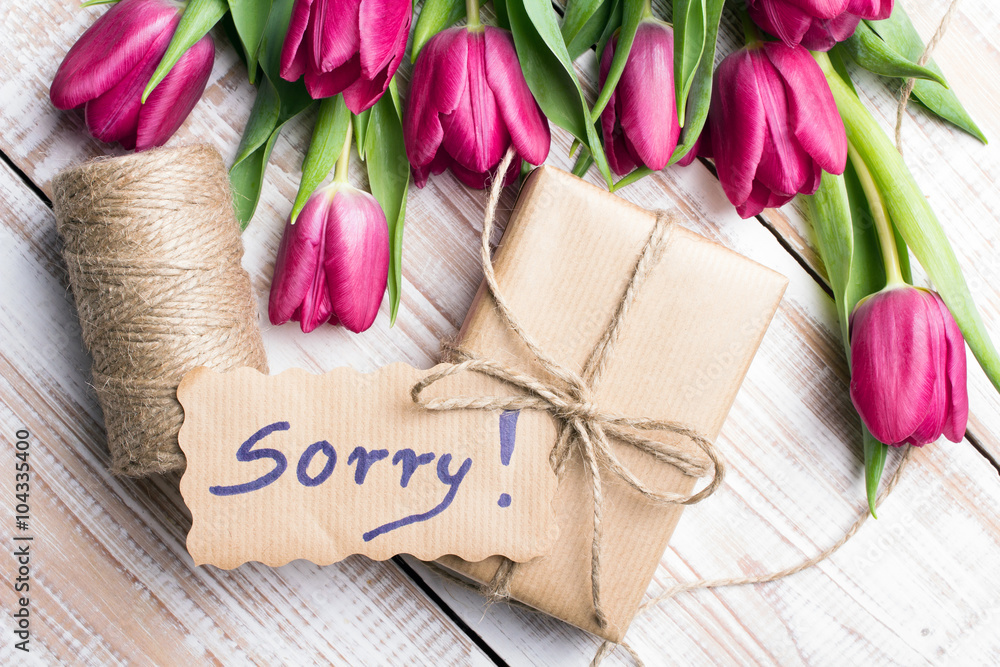 word SORRY and bouquet of tulips on wooden background word SORRY and bouquet of tulips on wooden background