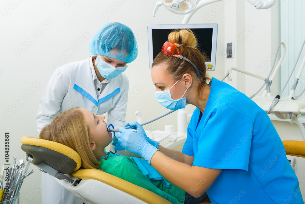 Dentist and nurse making professional teeth cleaning female young patient at the dental office Dentist and nurse making professional teeth cleaning female young patient at the dental office