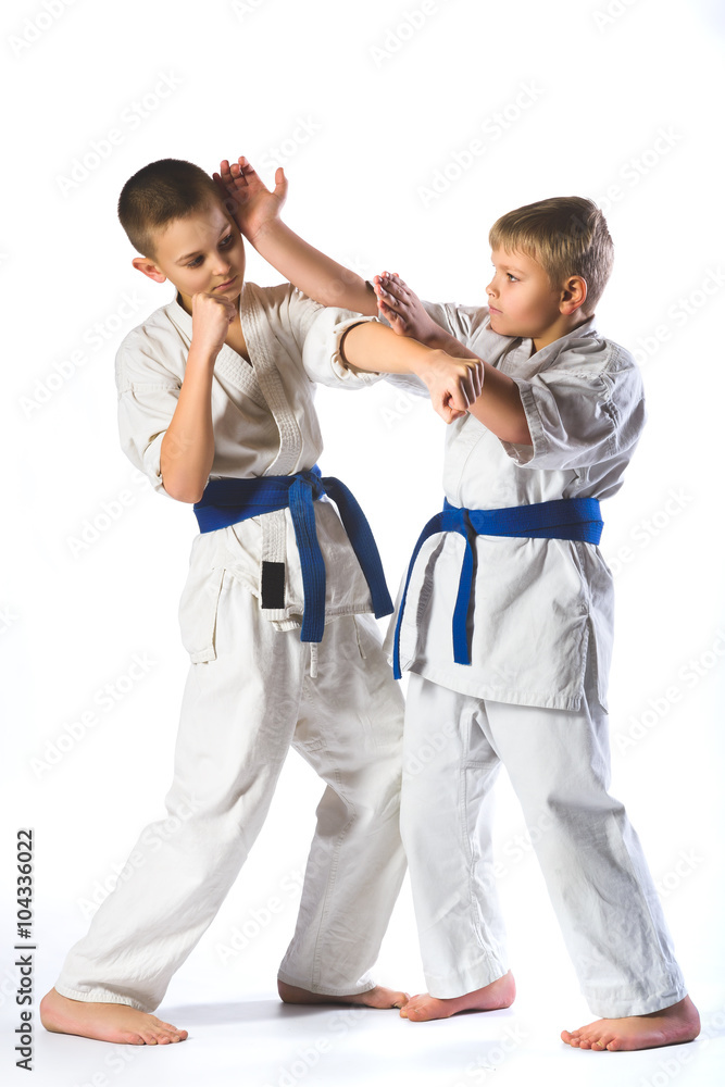 boys in kimono during training karate exercises on white background boys in kimono during training karate exercises on white background