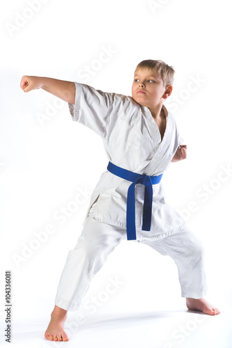 boy in kimono during training karate exercises on white background