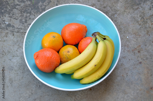 Bananas, valencia oranges and tangelos in large blue bowl