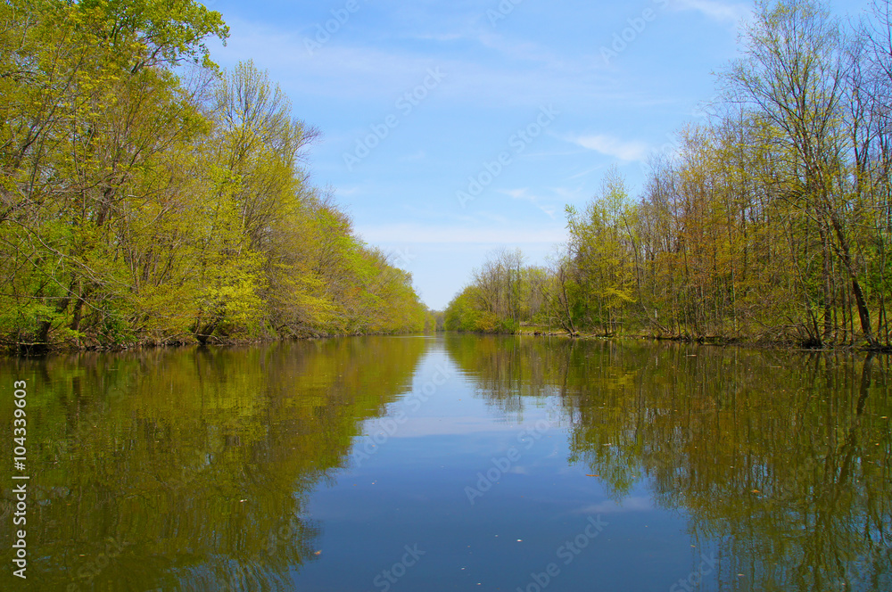Springtime view down the river with trees covered with first spring foliage along the banks. Springtime view down the river with trees covered with first spring foliage along the banks.