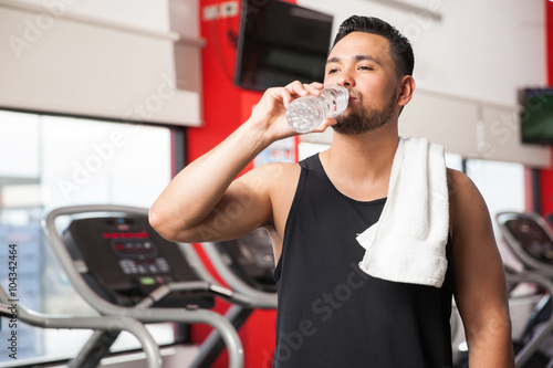 Young man drinking water in a gym