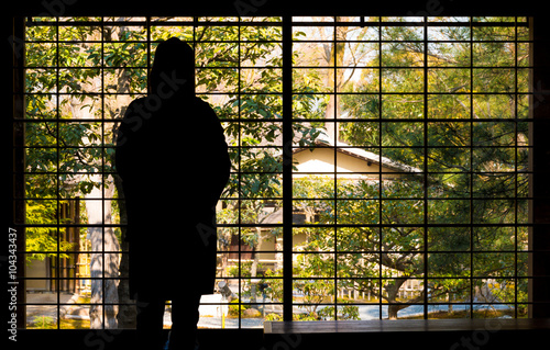 Silhouette of contemplative woman looking out a window