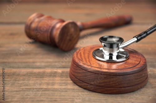 Stetoscope and Real Judges Gavel On Brown Wooden Background