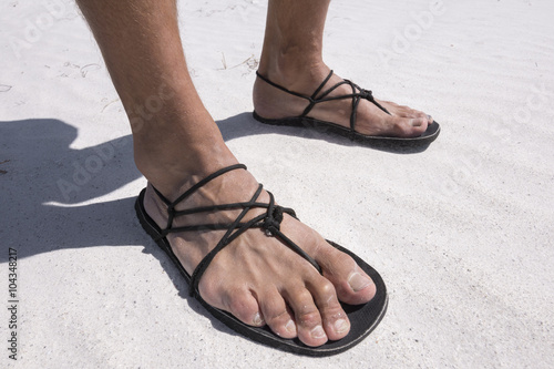 Closeup primitive sandals worn on beach © Shakzu