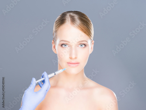 Doctor injecting botox in a beautiful face of a young woman. Plastic surgery concept.