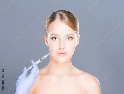 Doctor injecting botox in a beautiful face of a young woman. Plastic surgery concept.