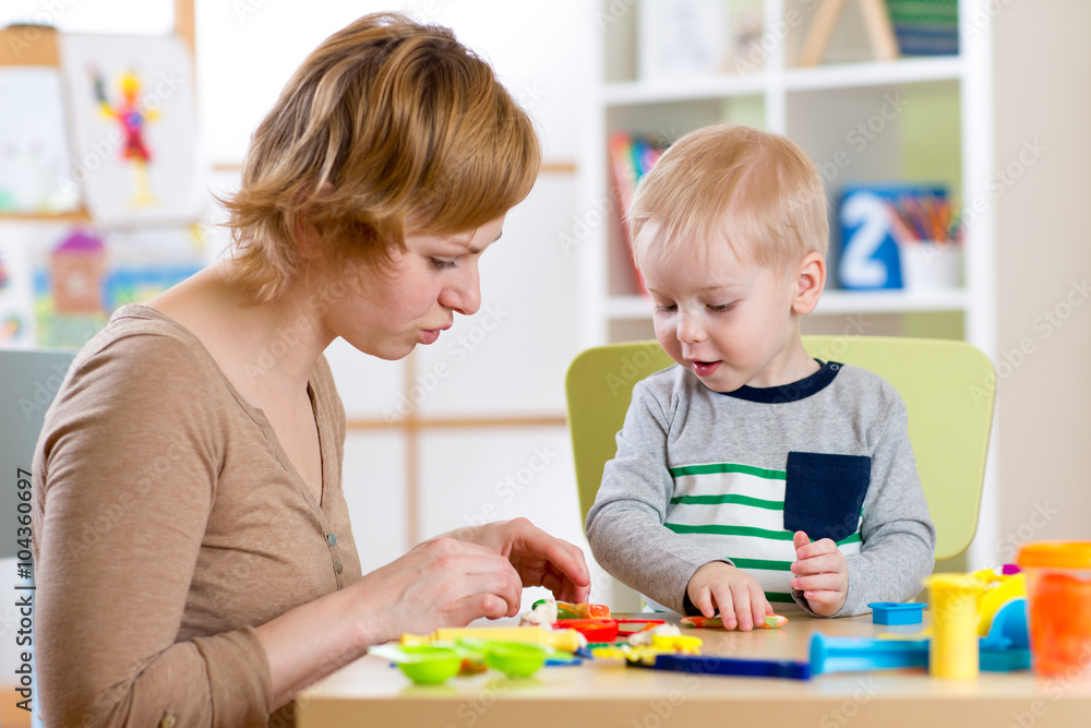 Child and woman play colorful clay toy in nursery Child and woman play colorful clay toy in nursery