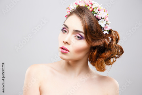Close-up portrait of beautiful young woman with perfect make-up and hair-style with flowers in hair