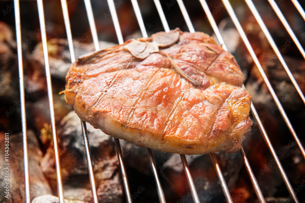 Grilled pork steaks over flames on the grill Grilled pork steaks over flames on the grill
