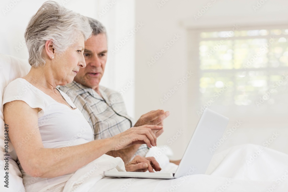 Senior couple using laptop at bed Senior couple using laptop at bed