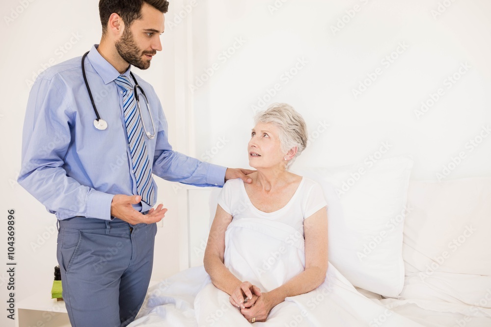 Fototapeta premium Handsome home nurse talking to elderly woman