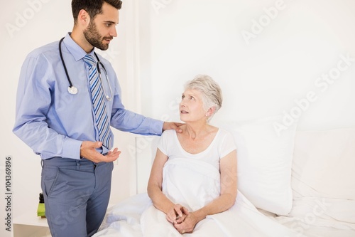 Handsome home nurse talking to elderly woman