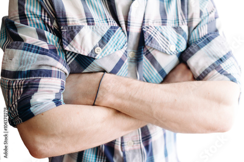Arms crossed. Hands of male in a checkered shirt close up on white background.