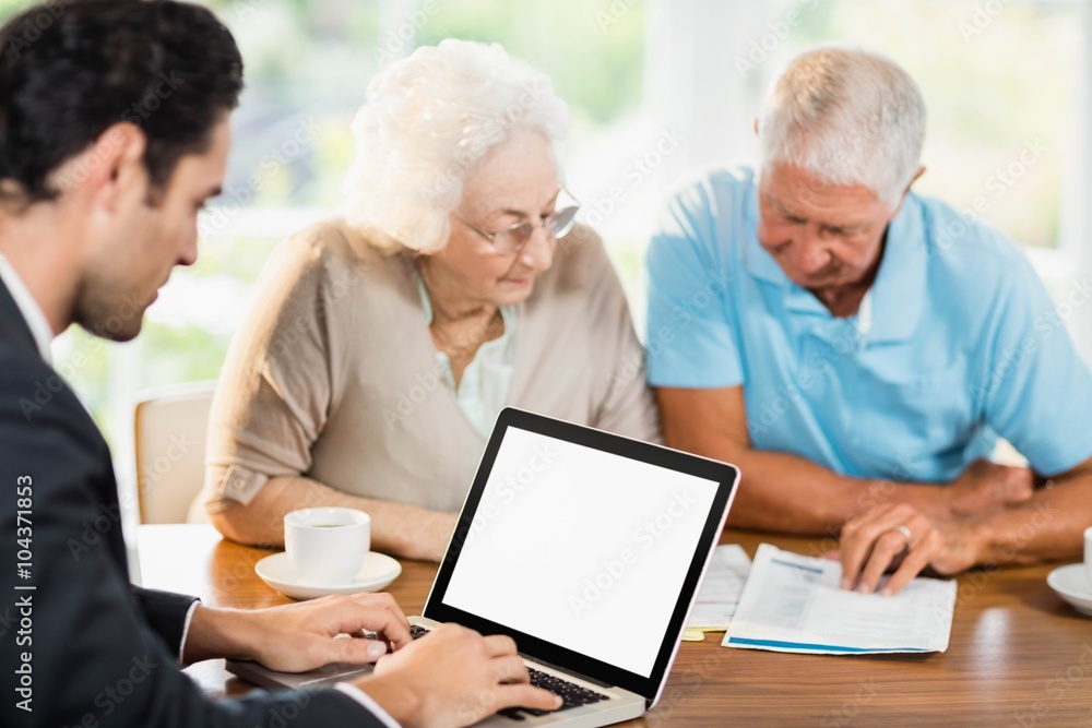 Businessman using laptop while senior couple is reading document Businessman using laptop while senior couple is reading document