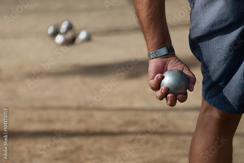 Senior men playing petanque, balls on the ground.