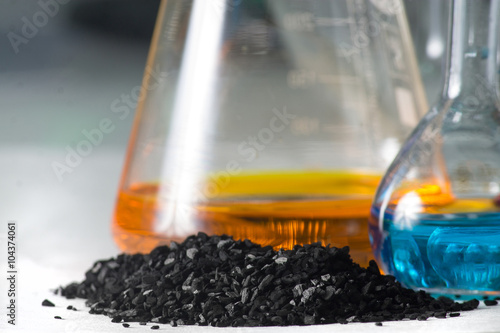 loose coal near the glass test tubes with colored liquid on grey