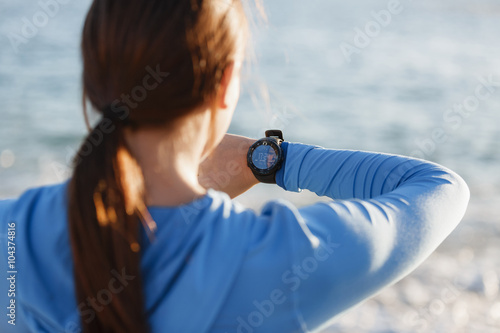 Runner woman with heart rate monitor running on beach