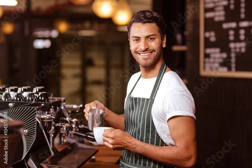 Obraz na płótnie Handsome waiter adding milk to coffee