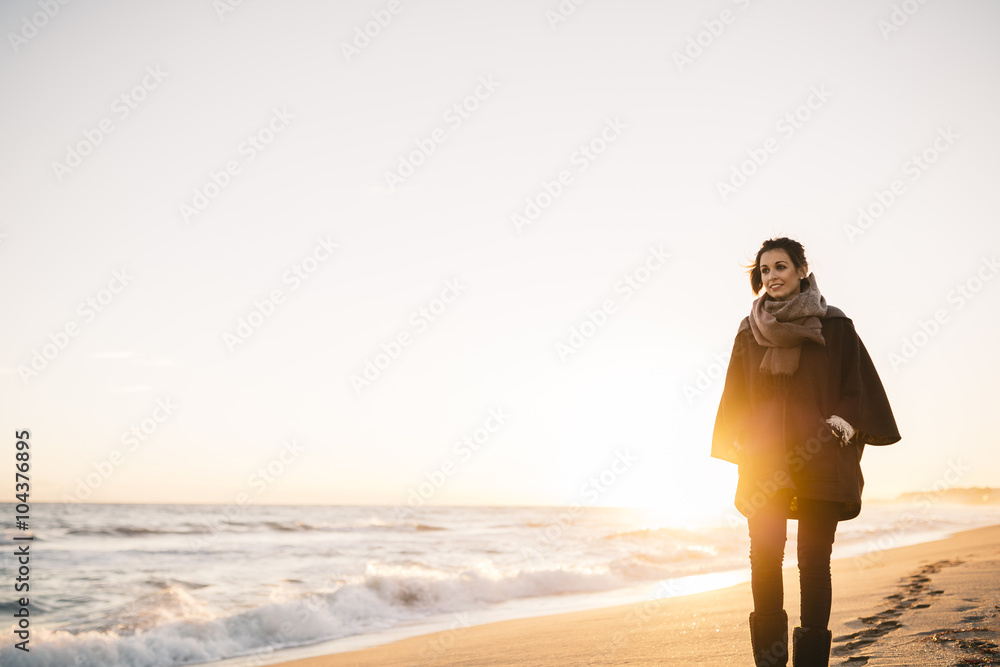 Young woman walking on the beach in winter Young woman walking on the beach in winter